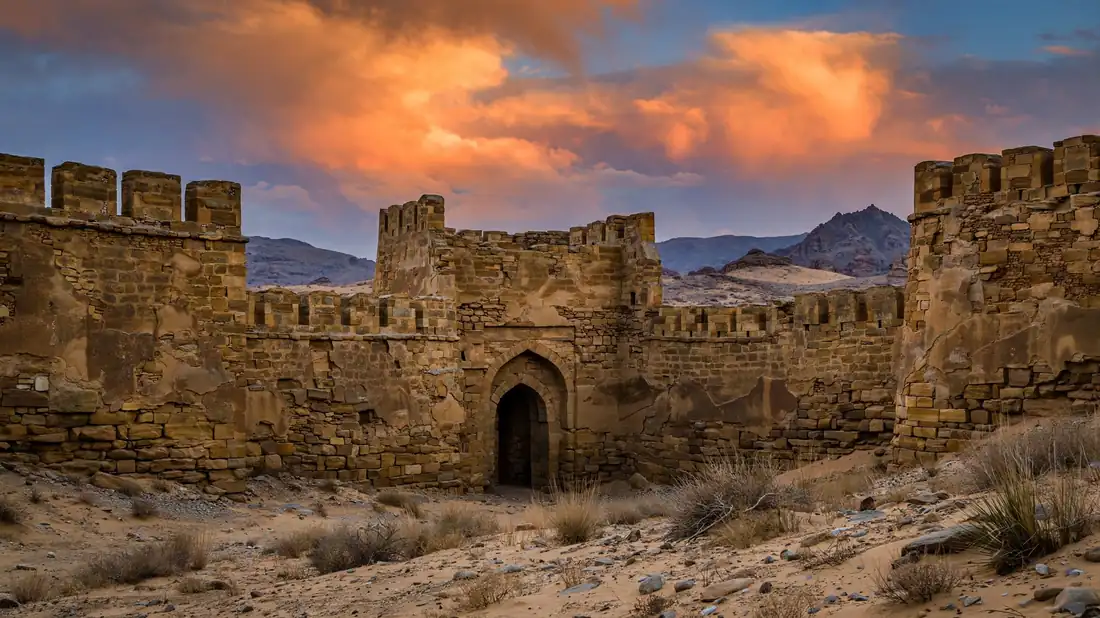 Massive ancient sandstone fortress walls at dusk, evoking the historic cities of Sindh