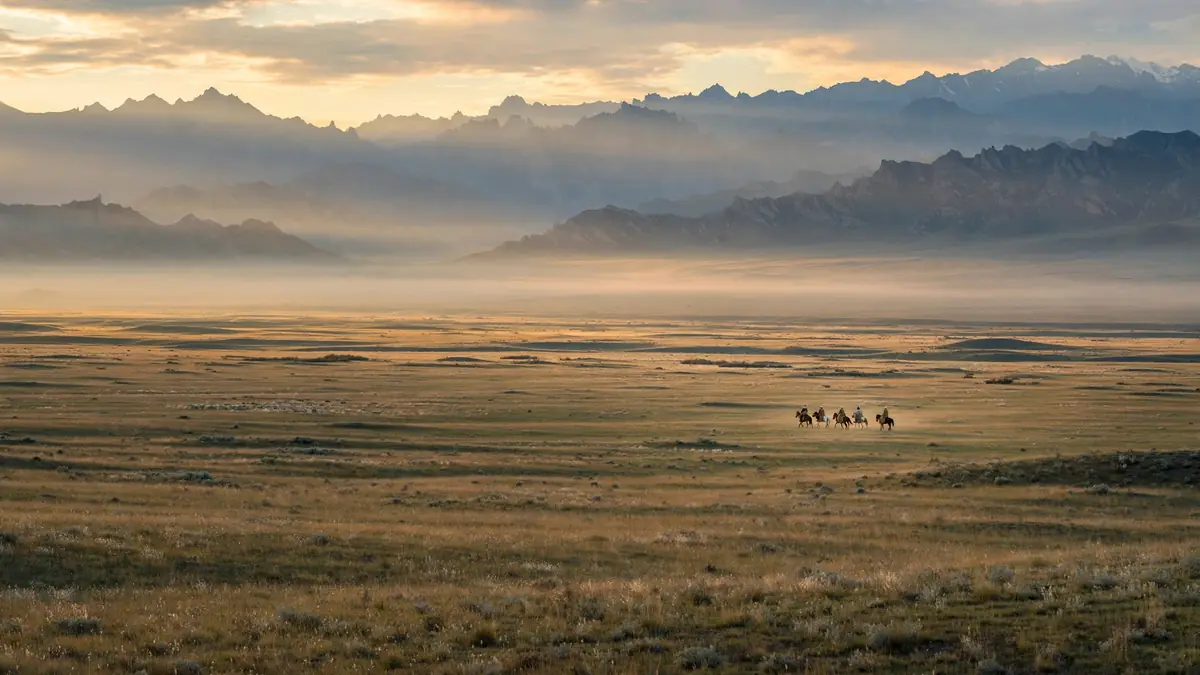 Silhouette of horsemen riding across the Central Asian steppe at dusk