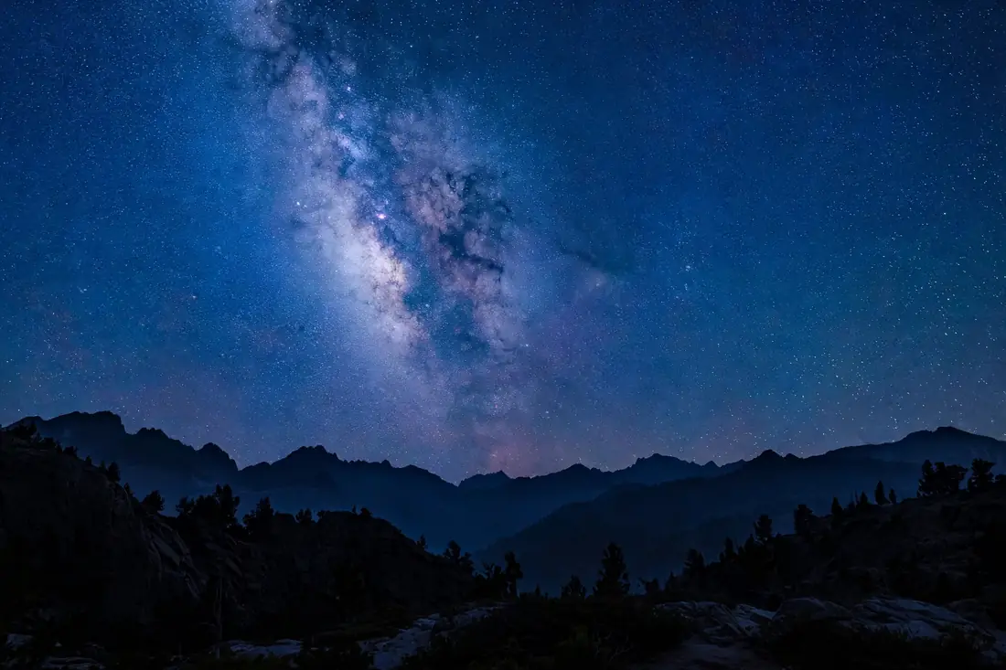 The Milky Way over dark mountain silhouettes at night