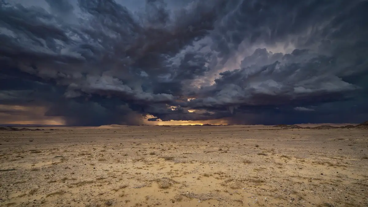 Dark stormy desert horizon with ominous gathering clouds, symbolizing the greatest trial of Dajjal